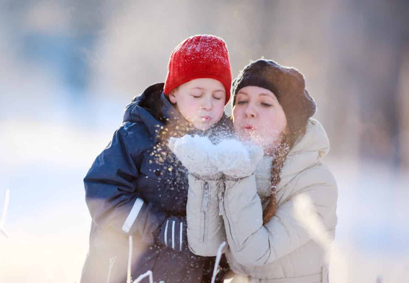 mum and boy blowing snow